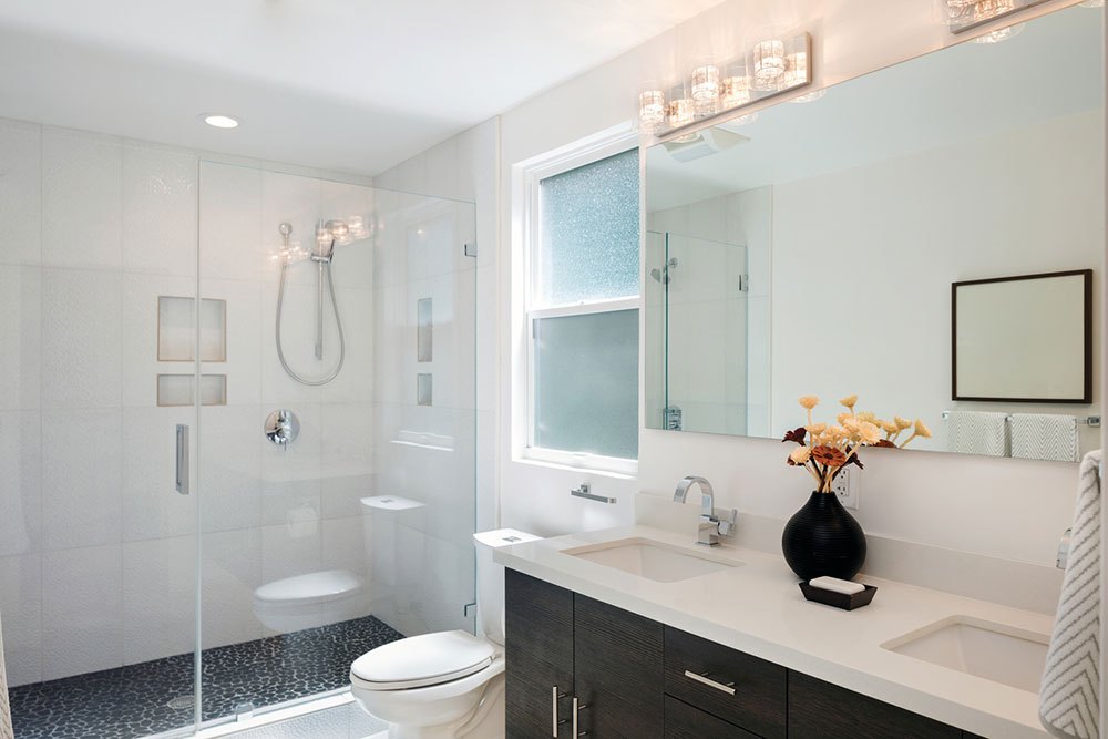 Modern bathroom interior with glass door shower and white cabinet with mirror.