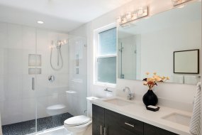 Modern bathroom interior with glass door shower and white cabinet with mirror.