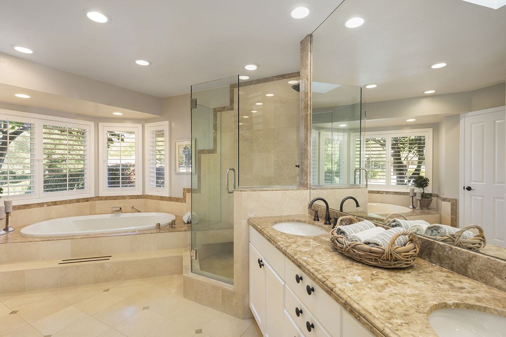 Luxury bathroom interior in marble with glass shower and round double sink.