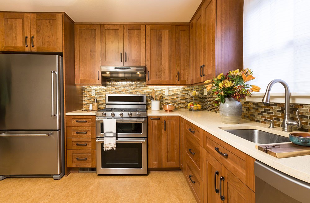 Contemporary upscale home kitchen interior with cherry wood cabinets, quartz countertops, sustainable recycled linoleum floors &amp; stainless steel appliances including refrigerator &amp; gas stove