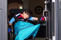 Disabled boy in wheelchair opening front door
